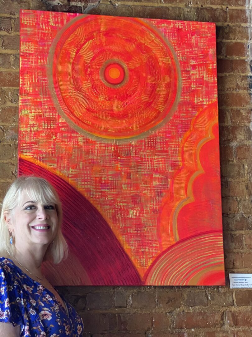 A woman standing next to an orange painting.